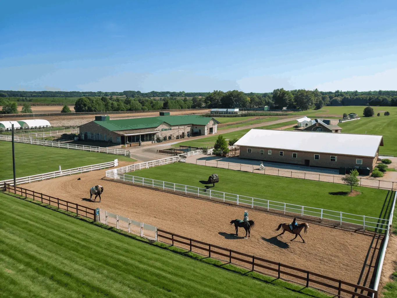 A photograph of ECURIE DU MAS's state-of-the-art equestrian facilities, including well-maintained stables, spacious riding arenas, and lush green pastures.